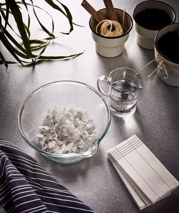 VERKLIGHET paper napkins, a large glass bowl with some shredded napkins and a jug of water next to it.