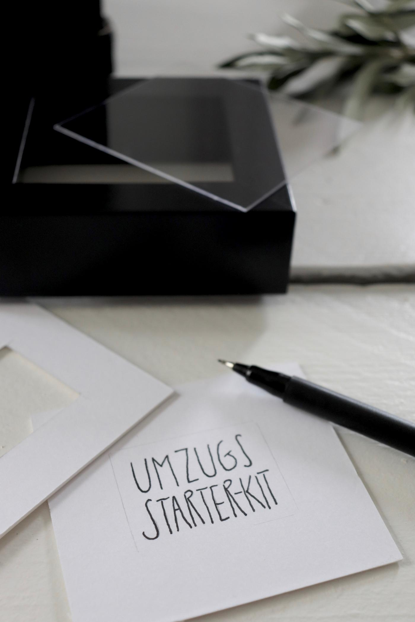 Verschiedene Utensilien neben einem Schild mit der Aufschrift "Umzugs-Starterkit".