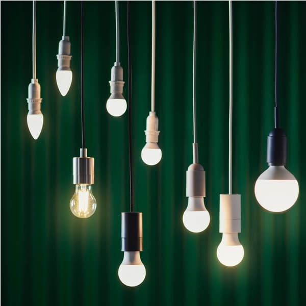 Verschillende hangende lampen en lichtbronnen verlichten een groene achtergrond. Mix van stijlen, vormen en energiezuinige verlichting.