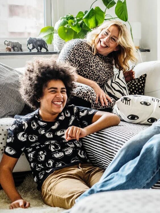 Vesela ženska in moški sedita na sedežni garnituri.