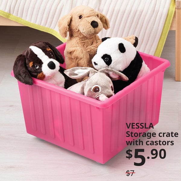 VESSLA storage crate with castors in pink, placed on the floor of a child's bedroom. Offer price: $5.90. Usual price: $.7. The crate is filled with soft toys.