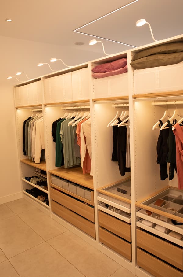 Vestidor format per un sistema PAX amb barra per a penjadors, calaixos extraïbles, sabater, espai d'emmagatzematge i il·luminació.