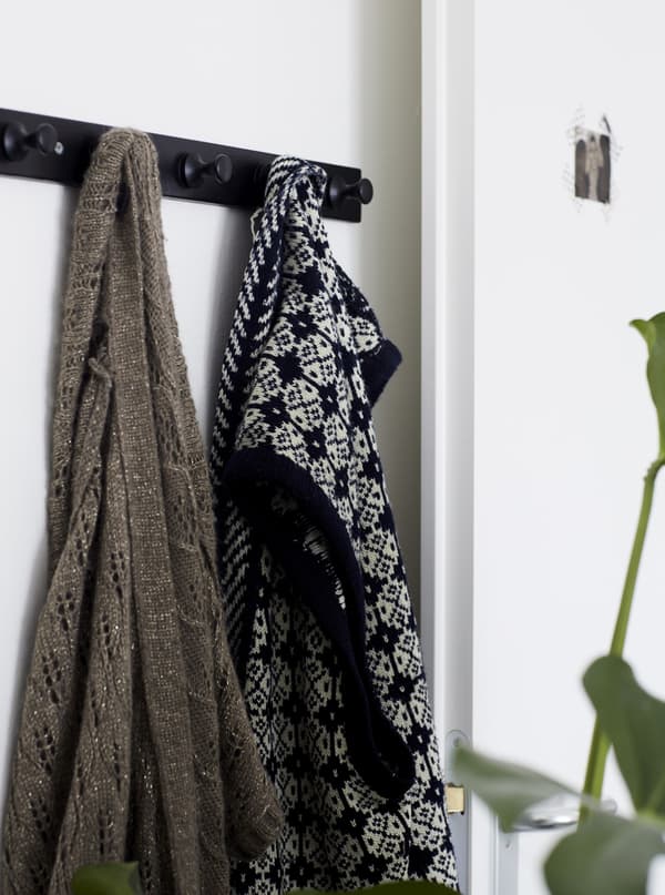 Vêtements accrochés à une patère dans une pièce blanche.