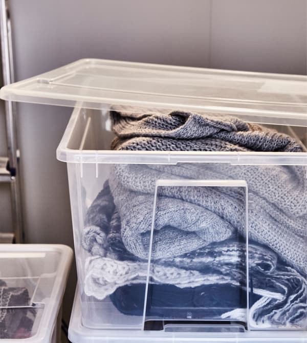 Vêtements d’hiver rangés dans des boîtes en plastique transparent empilables.