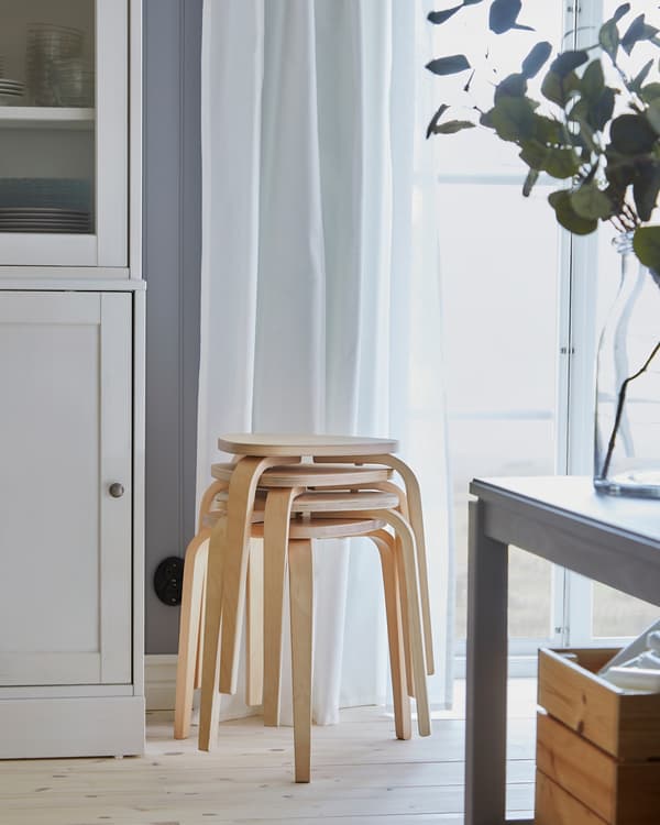 Vier KYRRE krukjes van berkenhout zijn opgestapeld bij een raam. Als je de eettafel uitschuift heb je zo extra zitplek.