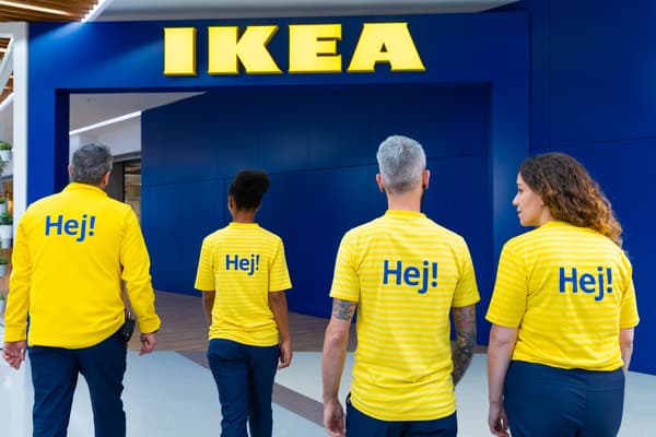 Vier Personen in gelben IKEA Tshirts stehen vor einer blauen Wand.