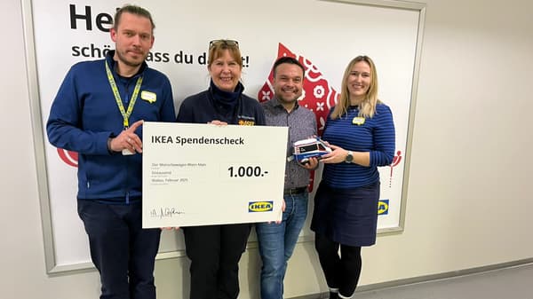 Vier Personen stehen in einem IKEA-Markt und halten gemeinsam einen grossen Spendenscheck in Höhe von 1'000 Euro für das Projekt 