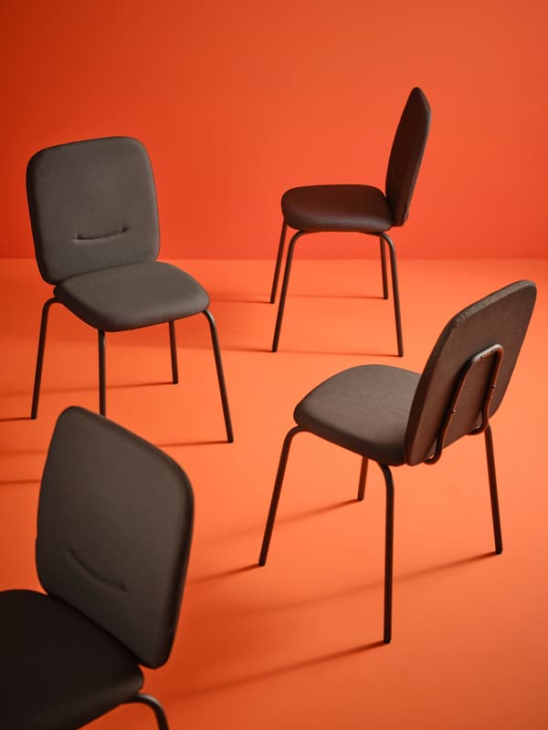Vier zwarte stoelen tegen een oranje achtergrond