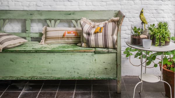 Vieux canapé vert avec des coussins contre un vieux mur de briques blanches