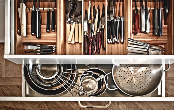 View from above of open kitchen drawers, showing pots and pans and piles of utensils in drawer compartments.