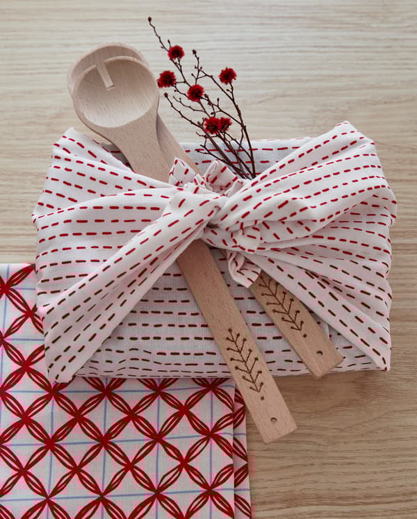 VINTERFEST red and white tea towels wrapped around utensils and a sprig of flowers.