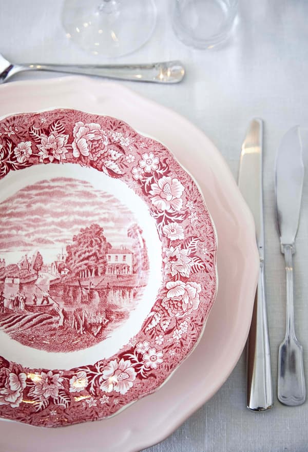 Vista aérea de decoración rústica con un plato blanco y rojo y cubiertos de estilo tradicional.