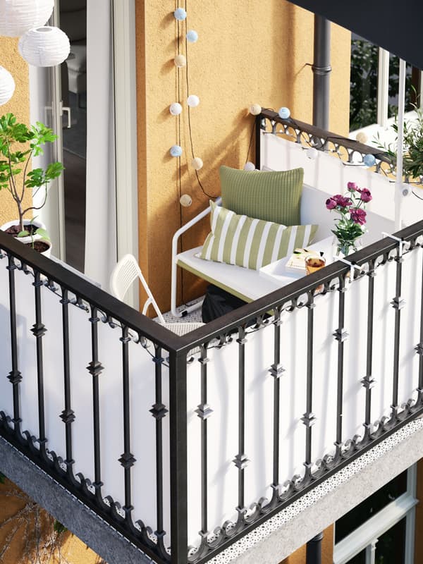 Vista dall'alto di un balcone con una seduta con cuscini sui toni del verde e alcune lucine decorative.