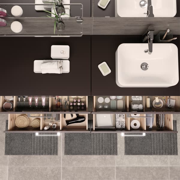 Vista de cima de quatro gavetas da casa de banho abertas com tudo muito bem organizado em caixas transparentes com compartimentos.