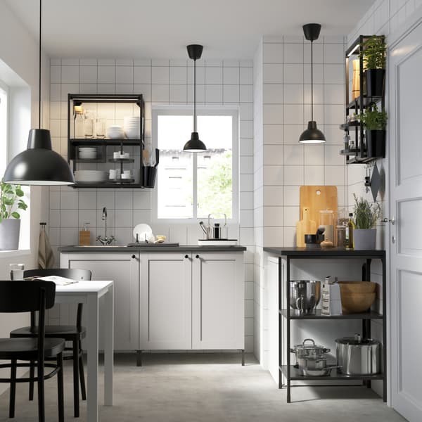 Vista de una cocina con muebles de la serie ENHET de IKEA. Predomina la combinación de muebles blancos y negros de madera.