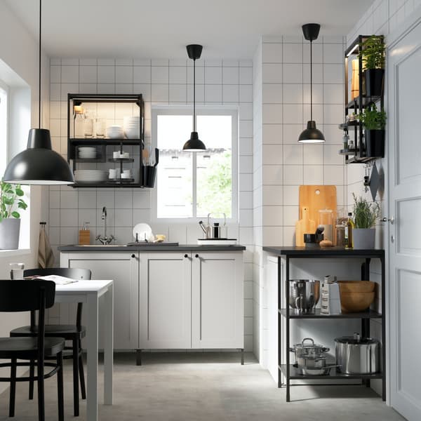 Vista frontal de una cocina con muebles ENHET con encimera gris y puertas blancas de diseño clásico. En los muebles superiores hay módulos abiertos con estructura de color negro. 
