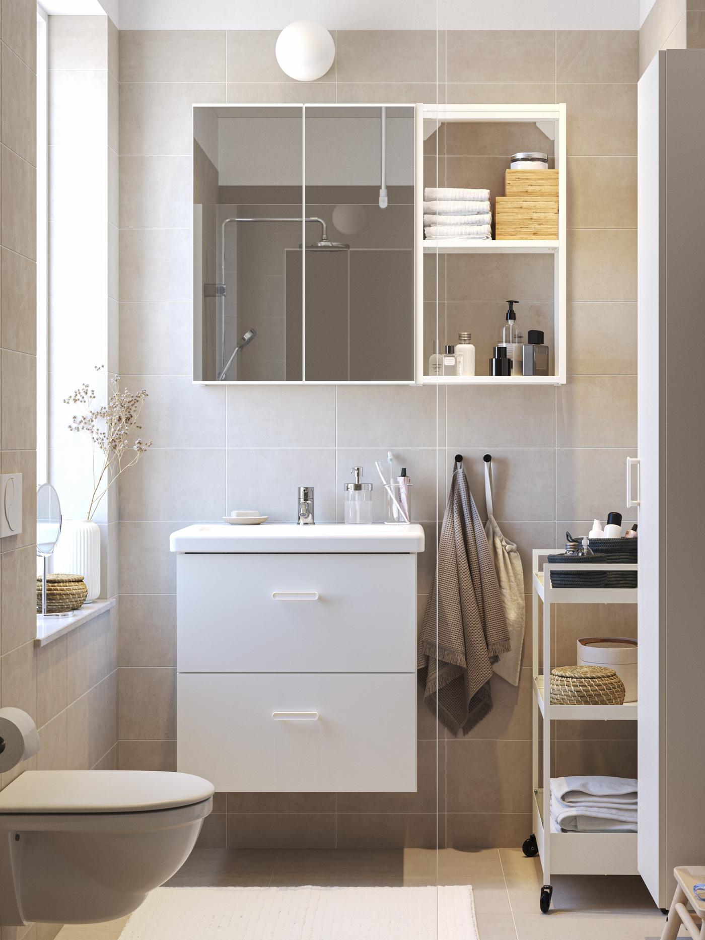 Vista frontale di un bagno con mobile lavabo bianco e uno specchio con pensile laterale bianco