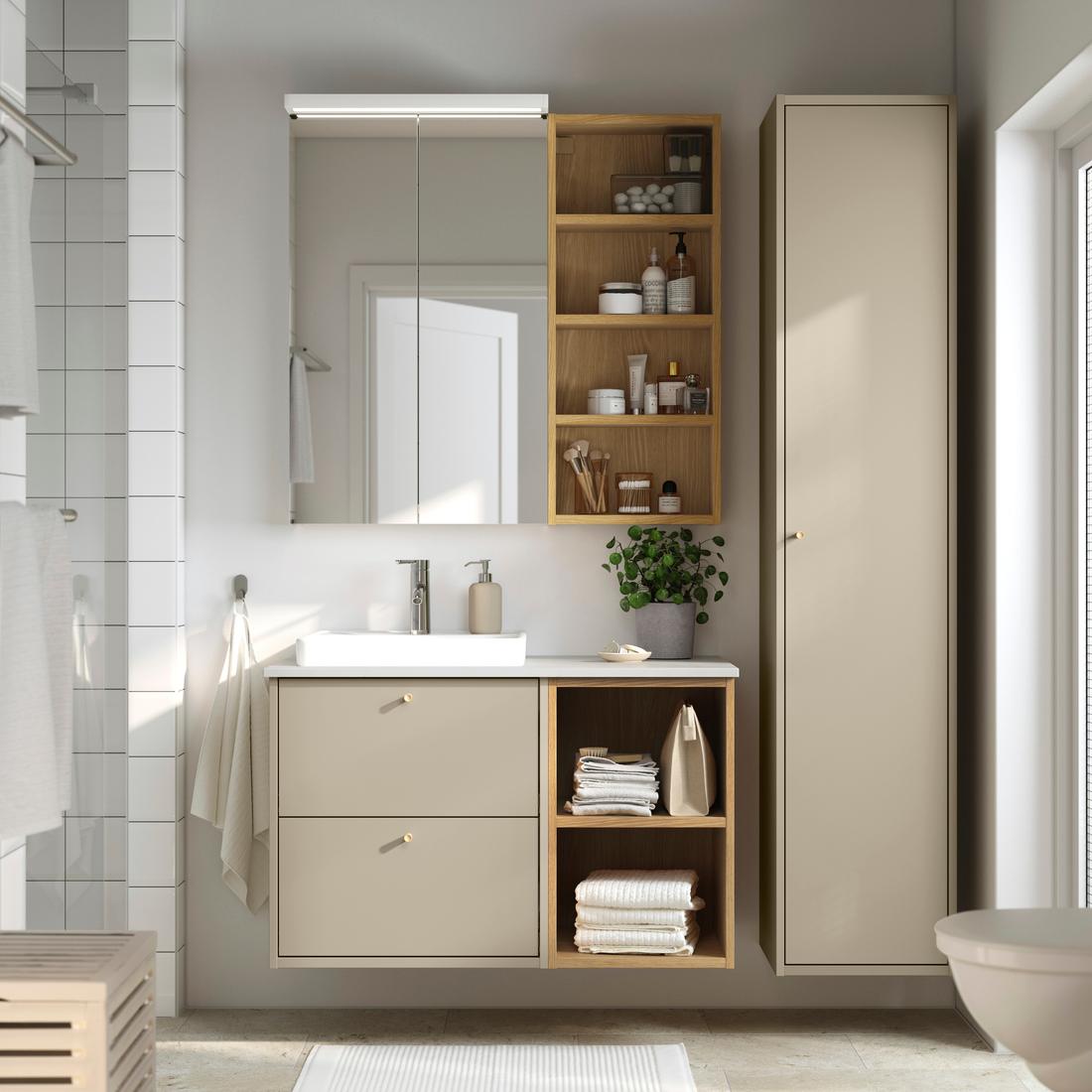 Vista frontale di un bagno HAVBÄCK beige composto da monile lavabo, mobile alto e pensile portaoggetti da parete. il labavo bianco ha un miscelatore inox.
