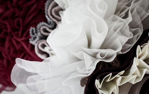 Visuale dal basso di alcuni tessuti appesi su uno stand appendiabiti MULIG.