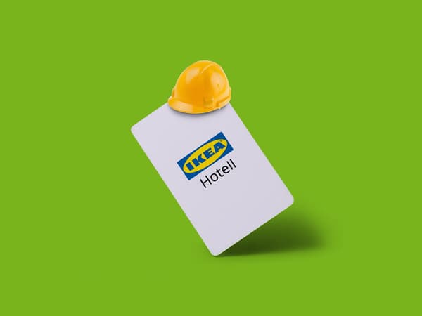 Vitt hotellkort med IKEA‑logotyp och texten “Hotell”, toppat med en gul bygghjälm, mot grön bakgrund.
