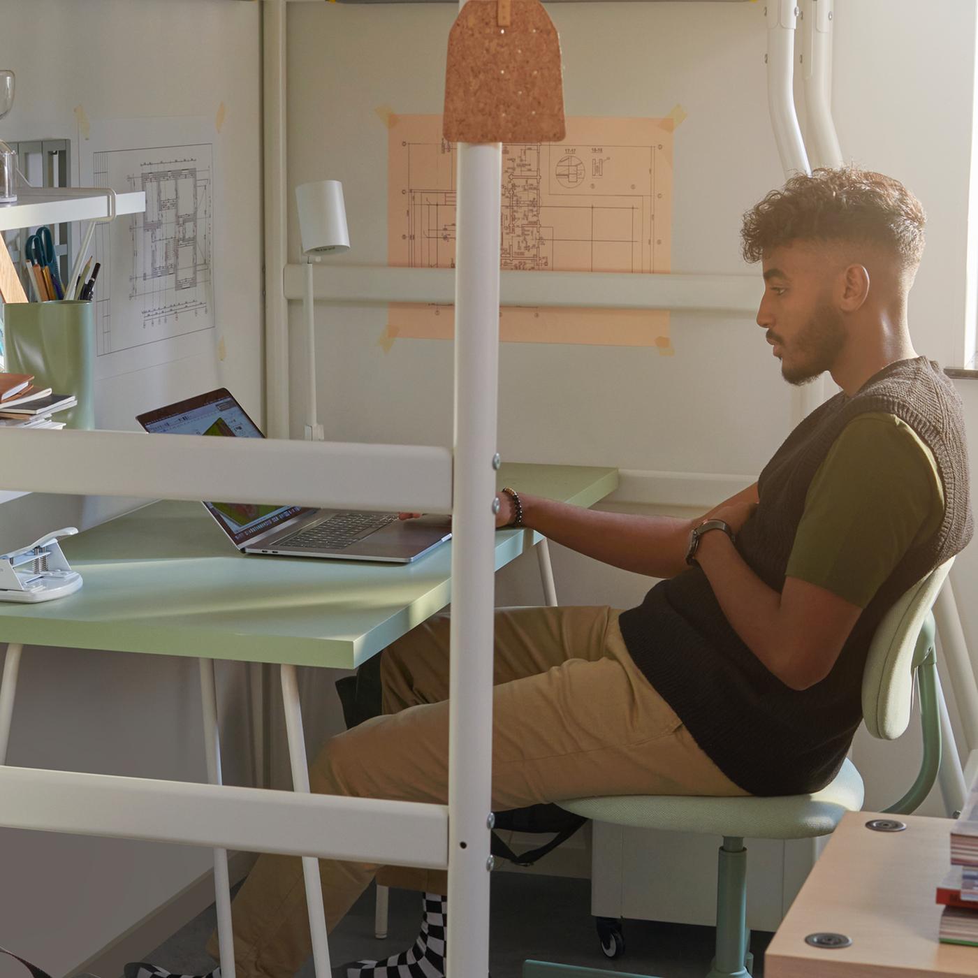 VITVAL/ヴィトヴァル ロフトベッドの下のLAGKAPTEN/ラグカプテン＆TILLSLAG/ティルスラーグ デスクに組み合わせたBLECKBERGET/ブレックベルゲット 回転チェアに男子学生が座っている。