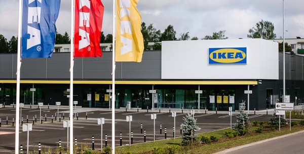 Внешний вид магазина IKEA: перед входом развеваются красные, жёлтые и синие флаги IKEA, почти пустая парковка и указатели направления к зоне погрузки (laadimisala) на эстонском языке.