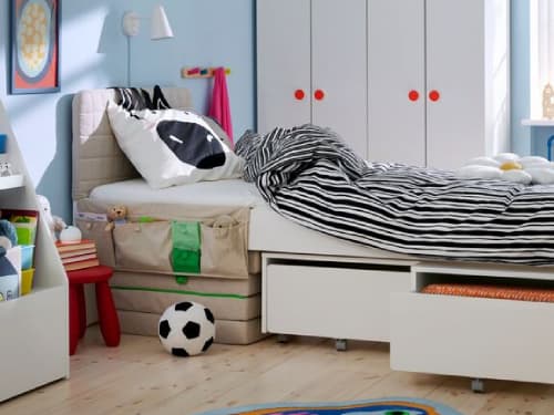 Volledig zicht op kinderkamer kamer met blauwe muren, het bed in het midden, kleerkasten achteraan, NATTHÄGER tapijt op de vloer.