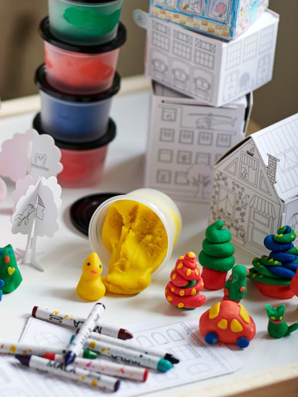 Voskovky MÅLA ležia na stole vedľa figúrok z plastelíny MÅLA.