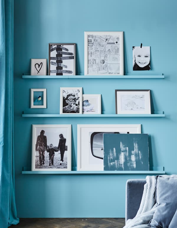 Vous recherchez des idées de mur de photos sympas ? Créez un mur de cadres photos dans votre séjour ! Pour un impact maximum, peignez les étagères pour photos dans la même couleur que le mur. Essayez l’étagère pour photos blanche MOSSLANDA de chez IKEA. Nous l’avons peinte dans un joli turquoise.