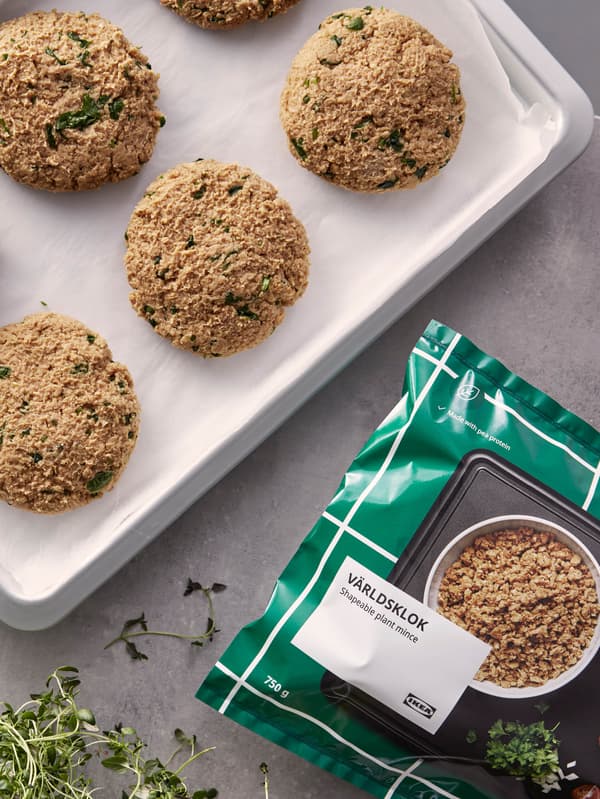 Vrecko s bezmäsitým mletým VÄRLDSKLOK je položené na stole vedľa plechu s vytvarovanými hamburgermi.