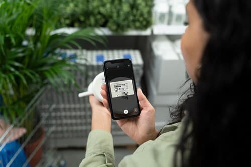 Vrouw met telefoon in haar handen met daarop de IKEA app