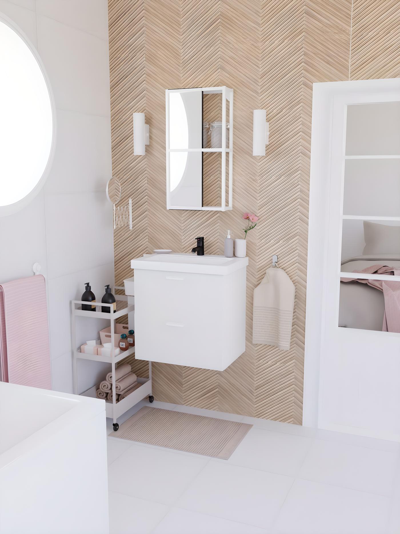 vue de biais d'une salle de bain blanche, dans une suite parentale, avec du linge de bain rose et beige, un mur de carrelage imitation chevron bois clair, et une baignoire blanche