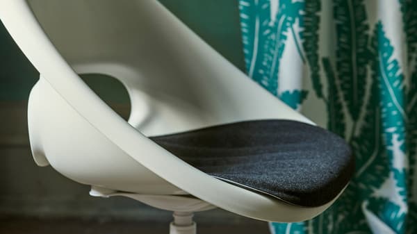 Vue rapprochée de la chaise pivotante blanche LOBERGET/BLYSKÄR avec un design rétro arrondi placé dans une pièce verte.