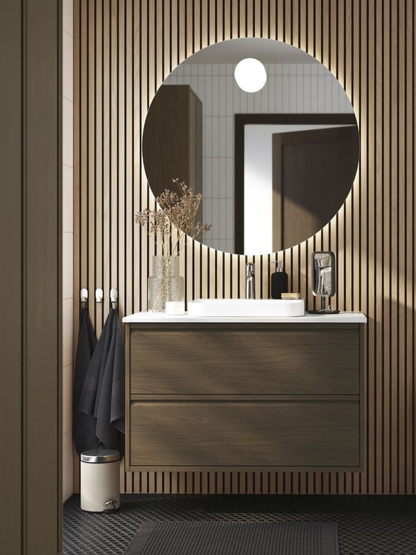 W pokoju stoi srebrno-ciemnoszary stolik do przechowywania KVISTBRO z narzutą w środku. Nad stolikiem wisi klosz LÖKNÄS.