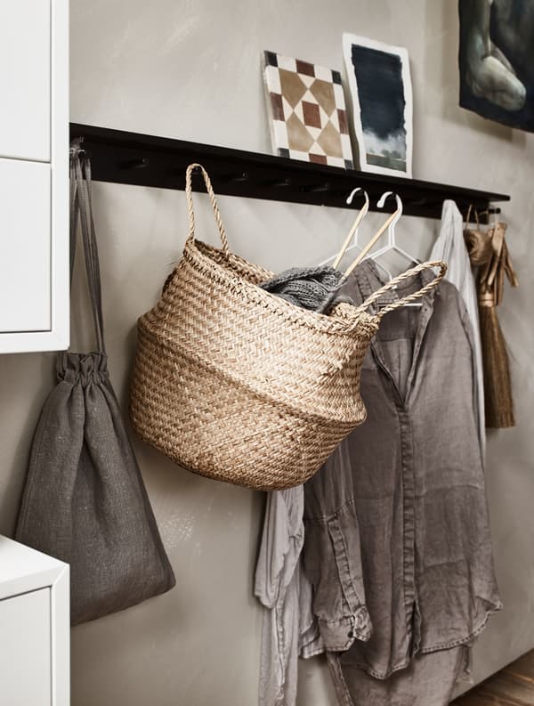 Wall hooks hold clothes on hangers, a basket, and more.