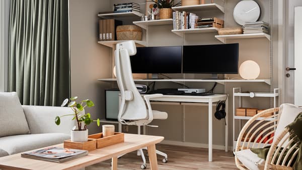 Wall-mounted shelving with two computer screens and books, a coffee table in ash veneer and beige/white office chair.