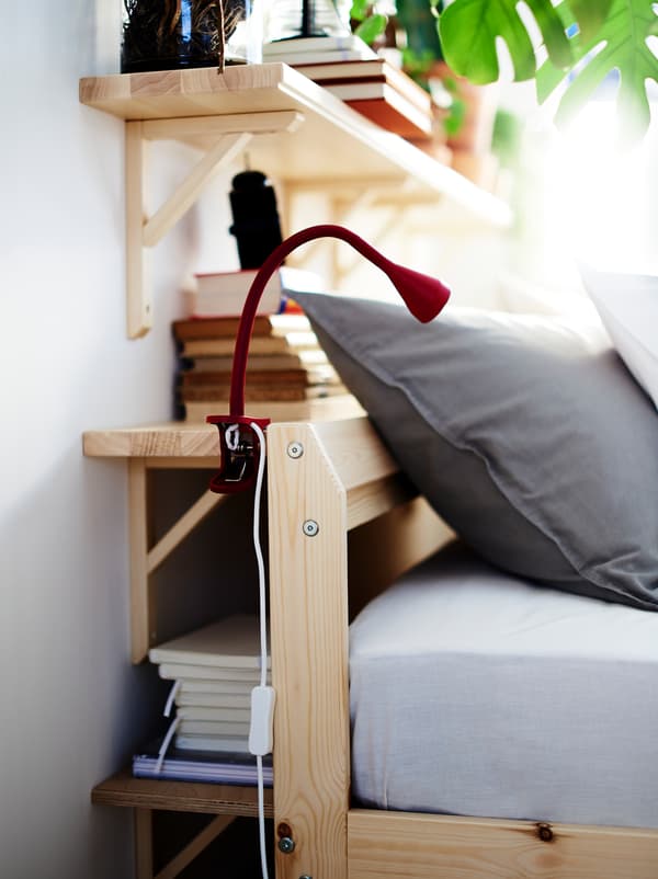 Wall shelves fill the space between a wall and the head end of a bed, creating a combination of storage and bedside table.