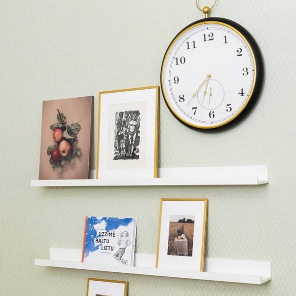Wall shelves with framed art, books, and decorative wall clock in minimalist interior
