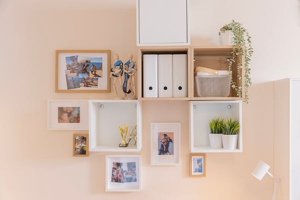 Wall shelves with framed photos, trophies, plants, and decorative items.