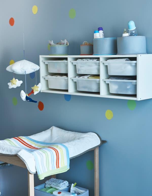 Wall storage placed above a changing table during infant years can be moved down to floor level later for toy storage