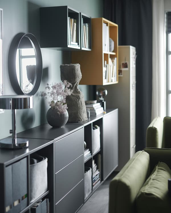 Wandgemonteerde EKET kasten in geel en antraciet. Ze hebben verschillende dieptes en sommige hebben deuren en laden.