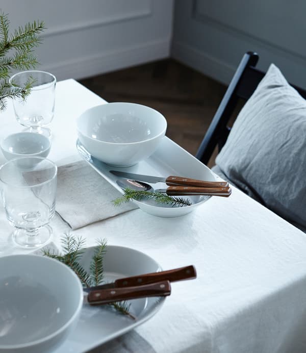 Want to impress with your festive table setting? Put together place settings that fit a theme. We used light textiles and light tableware (e.g. IKEA 365+ serving plates in white) with evergreen pine branches.