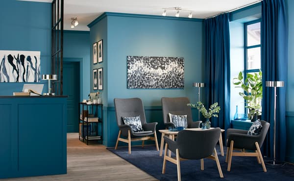 Wartebereich für Gäste in blau mit 4 VEDBO Sesseln, einem LISABO Tisch, Wandbildern & Pflanzen.