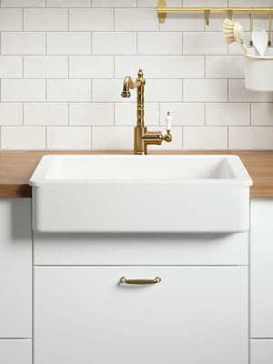 Waschbecken mit weißem Rand verbaut in einer Küche mit weißen Fronten und Arbeitsplatte aus Holz