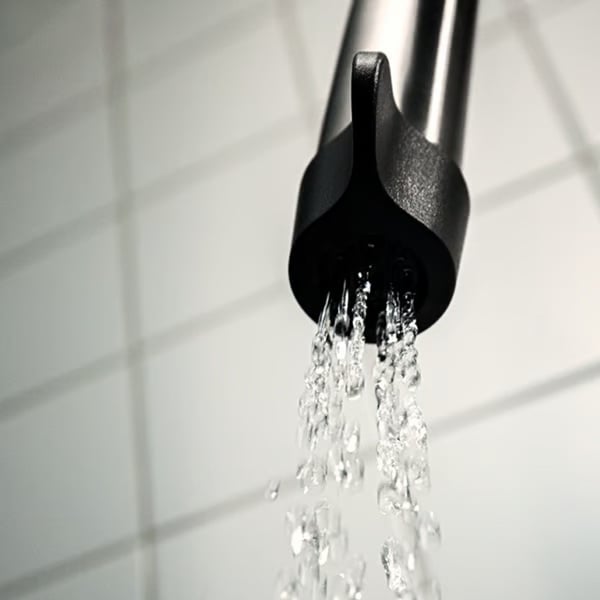 Water flows from a tap, showing the nozzle releasing a steady stream.