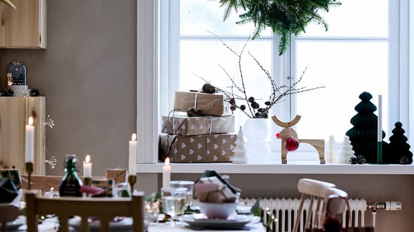 Weihnachtlich gedeckter Tisch vor einer ebenfalls weihnachtlich geschmückter Fensterbank