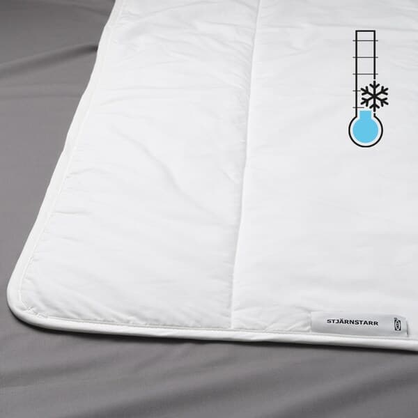 Weiße Bettdecke auf grauem Untergrund. Oben rechts ein Symbol mit Thermometer, Schneeflocke und blauem Temperaturbalken. An der Auflage ist ein kleines Etikett mit dem Markennamen „IKEA“ befestigt.