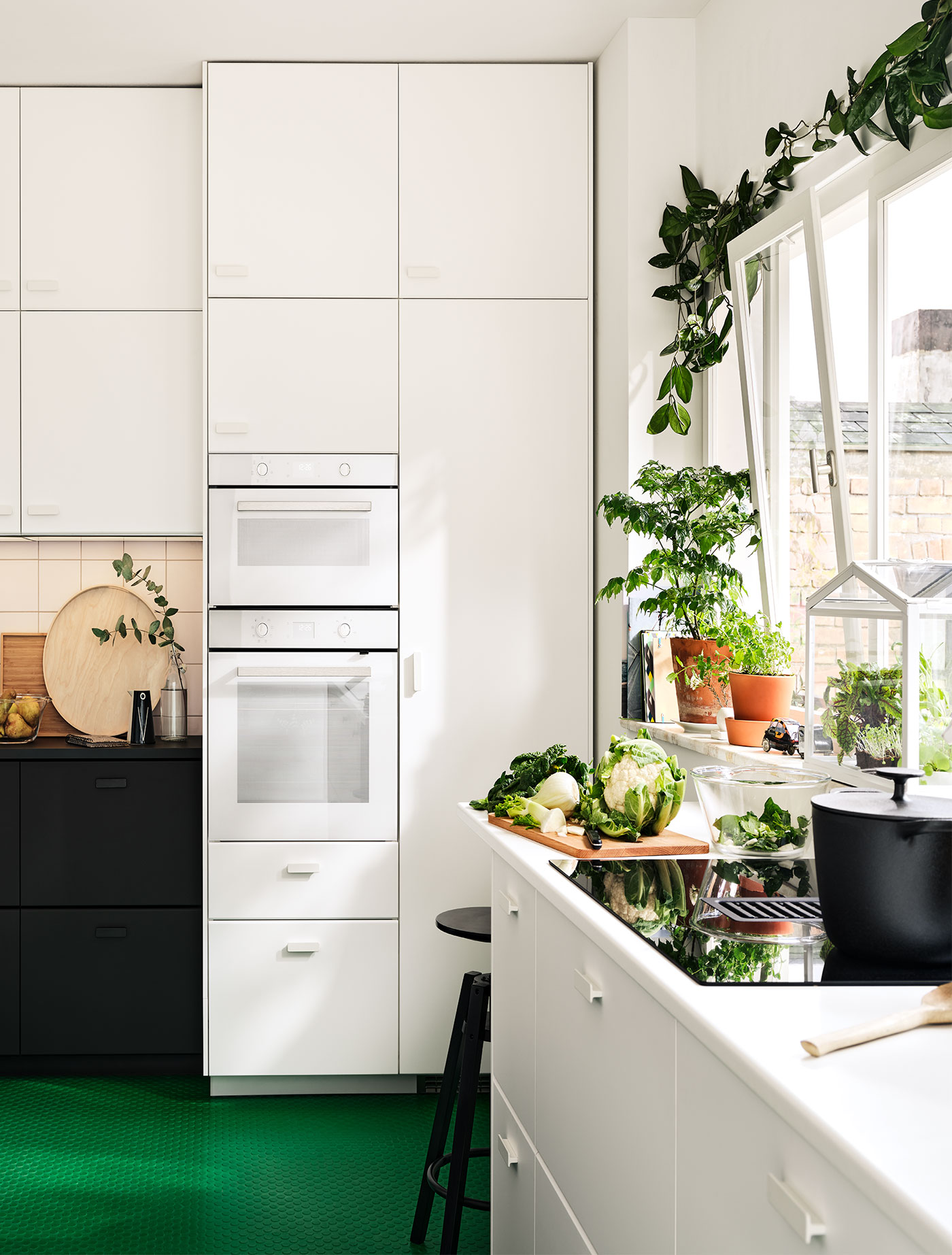 Weiße METOD Küche mit grünem Boden und Pflanzen.