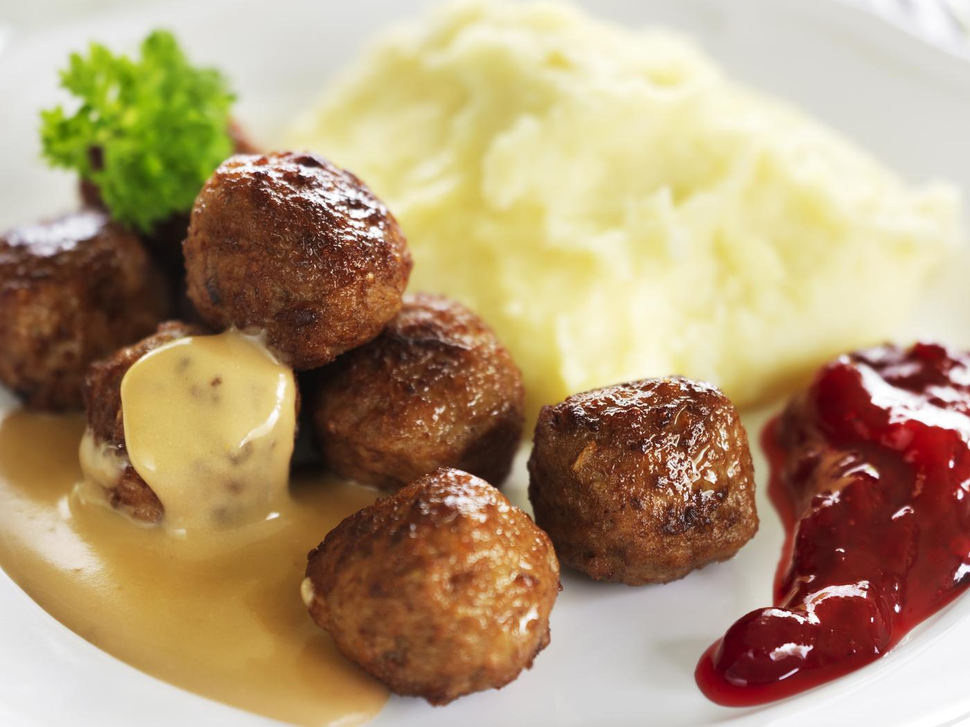 weißer Teller, darauf Fleischbällchen (KÖTBULLAR) mit Kartoffelpüree, Sauce und Preiselbeeren