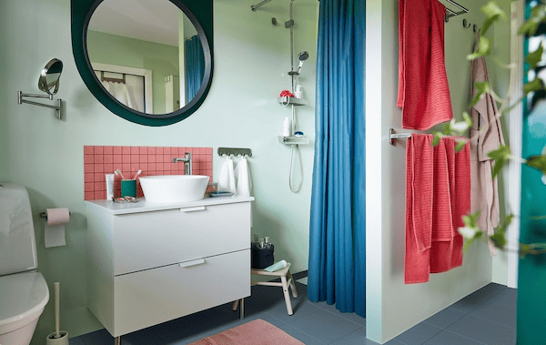 Well organised bathroom interior in soft pastels complete with washstand, shower, towel rail, mirror, plants and accessories.
